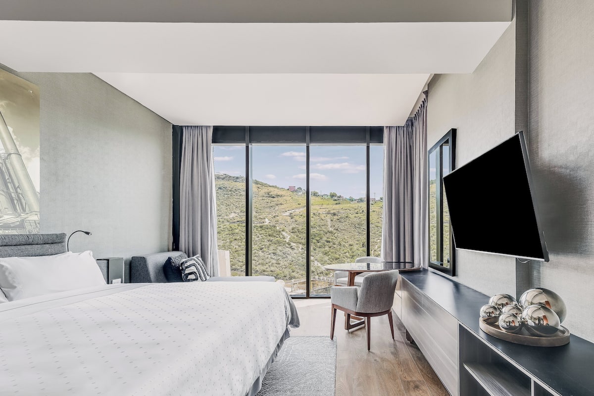 Una habitación de hotel moderna con una cama grande, un escritorio y un televisor.