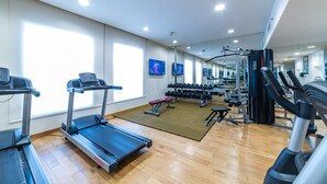 Ein Fitnessstudio mit Laufbändern, Kurzhanteln und Krafttrainingsgeräten.