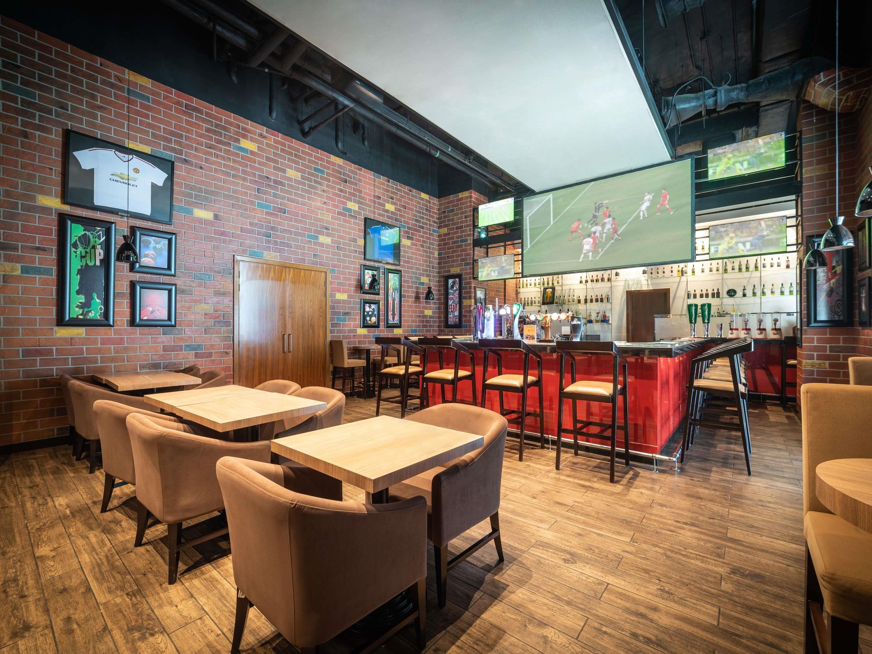 A bar area with wooden tables and chairs, a brick wall, and sports memorabilia.