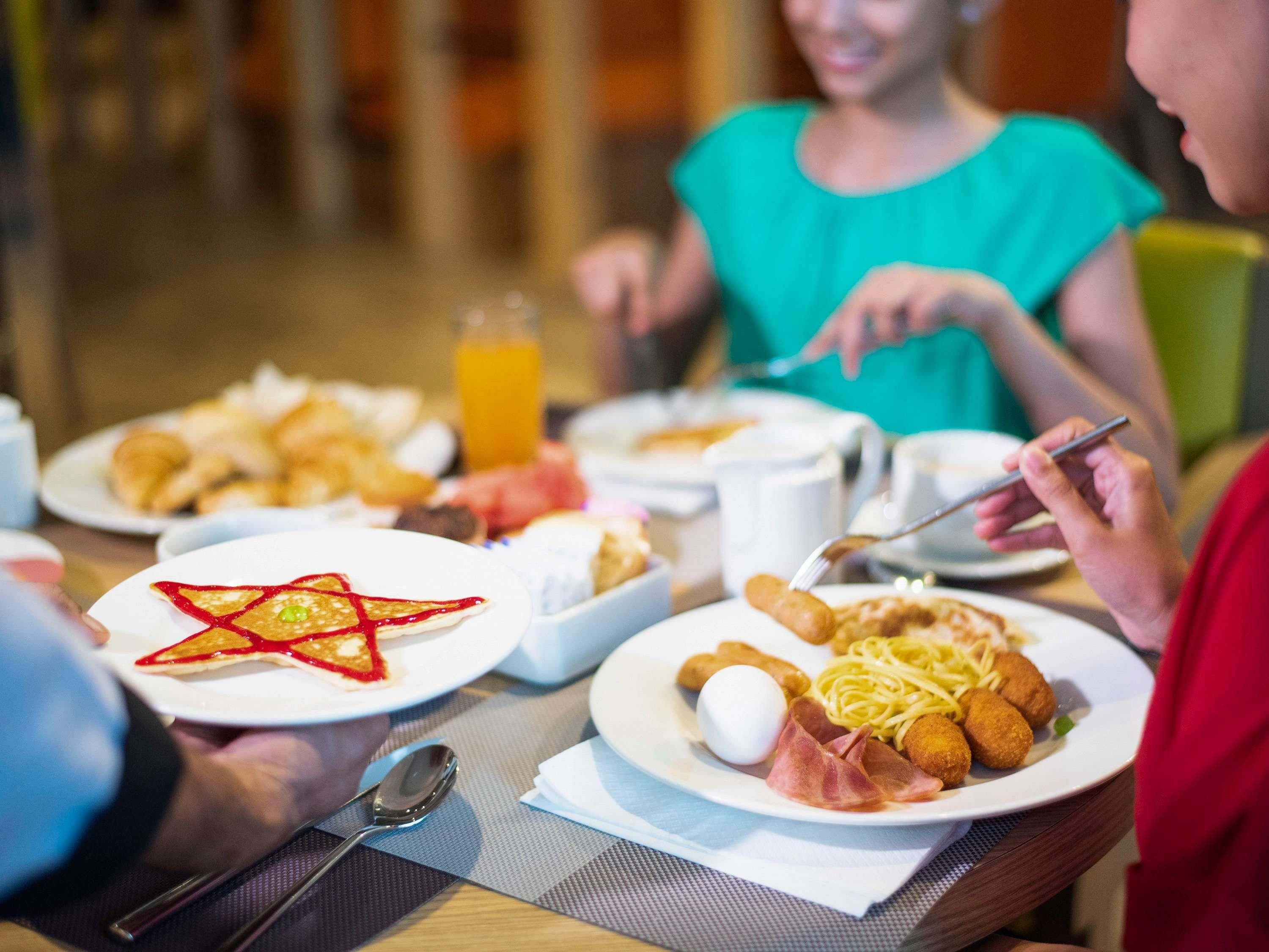 A breakfast setting with plates of food, a bottle of orange juice, and a spoon on a table.