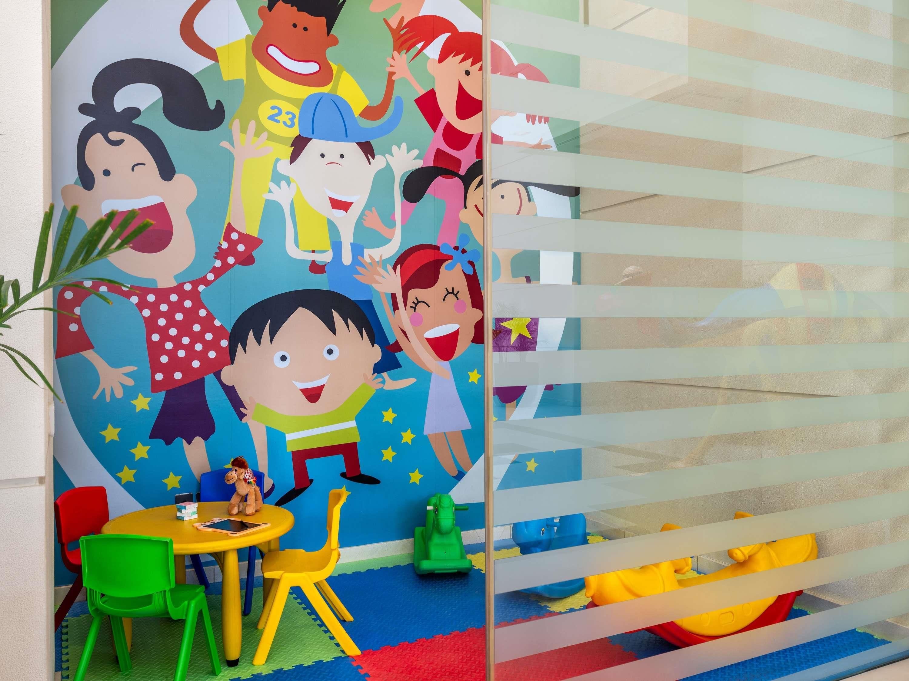 A children's play area with colorful toys and a mural of cartoon characters.