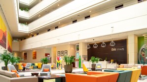 Un'ampia hall con diverse zone salotto, una reception e una pianta grande.