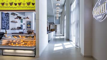 A modern restaurant interior with a long counter, a glass display case with food items, and a sign reading "The Market Restaurant."