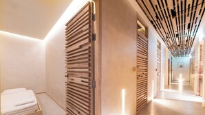 Un corridoio moderno di un hotel con porte a listelli di legno, un letto rifatto e un lungo corridoio ben illuminato.