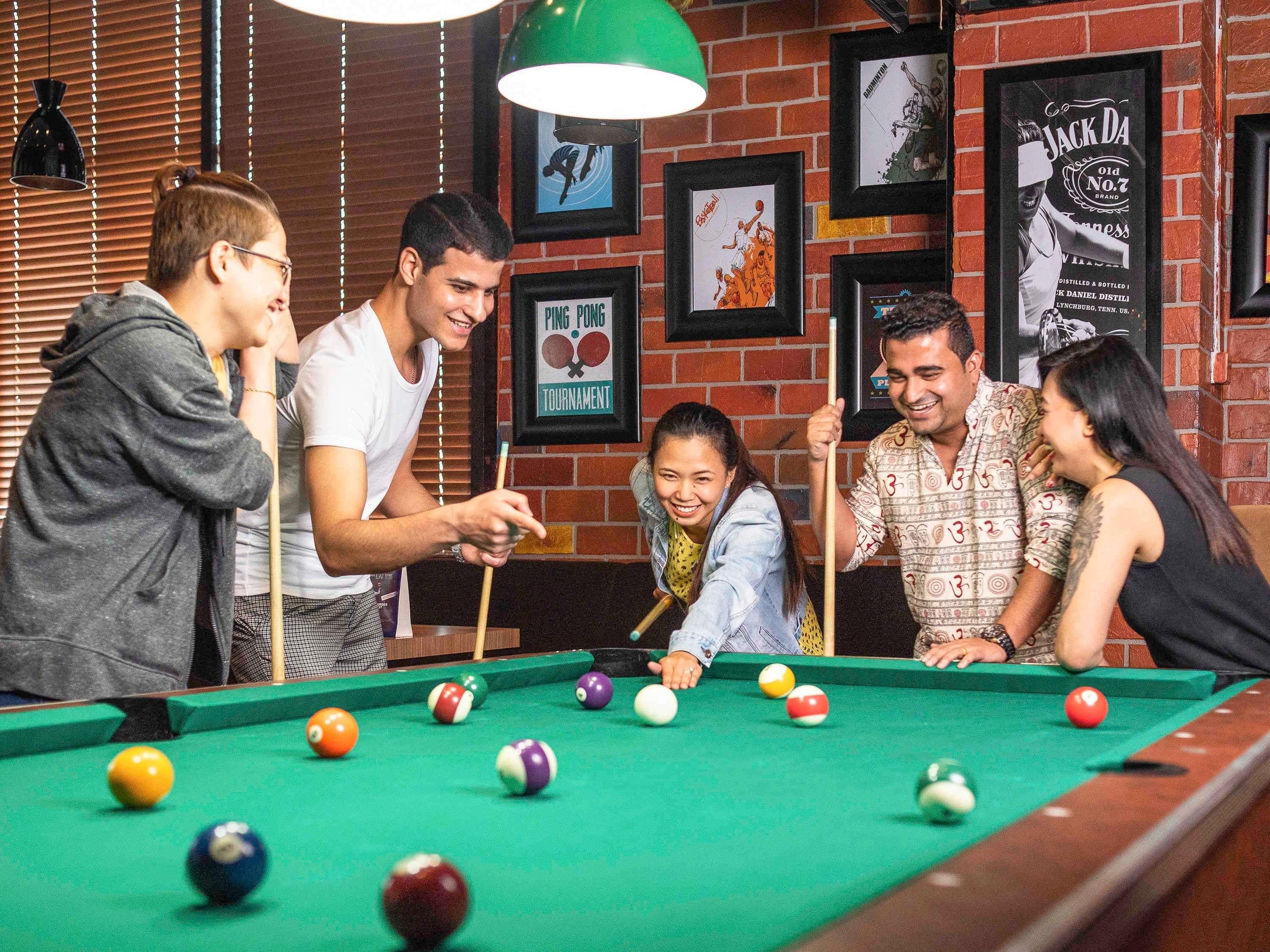 A pool table in a room with brick walls and framed pictures.