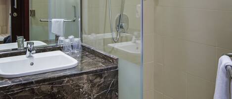 A modern bathroom with a glass-enclosed shower, a marble sink, and a large mirror.
