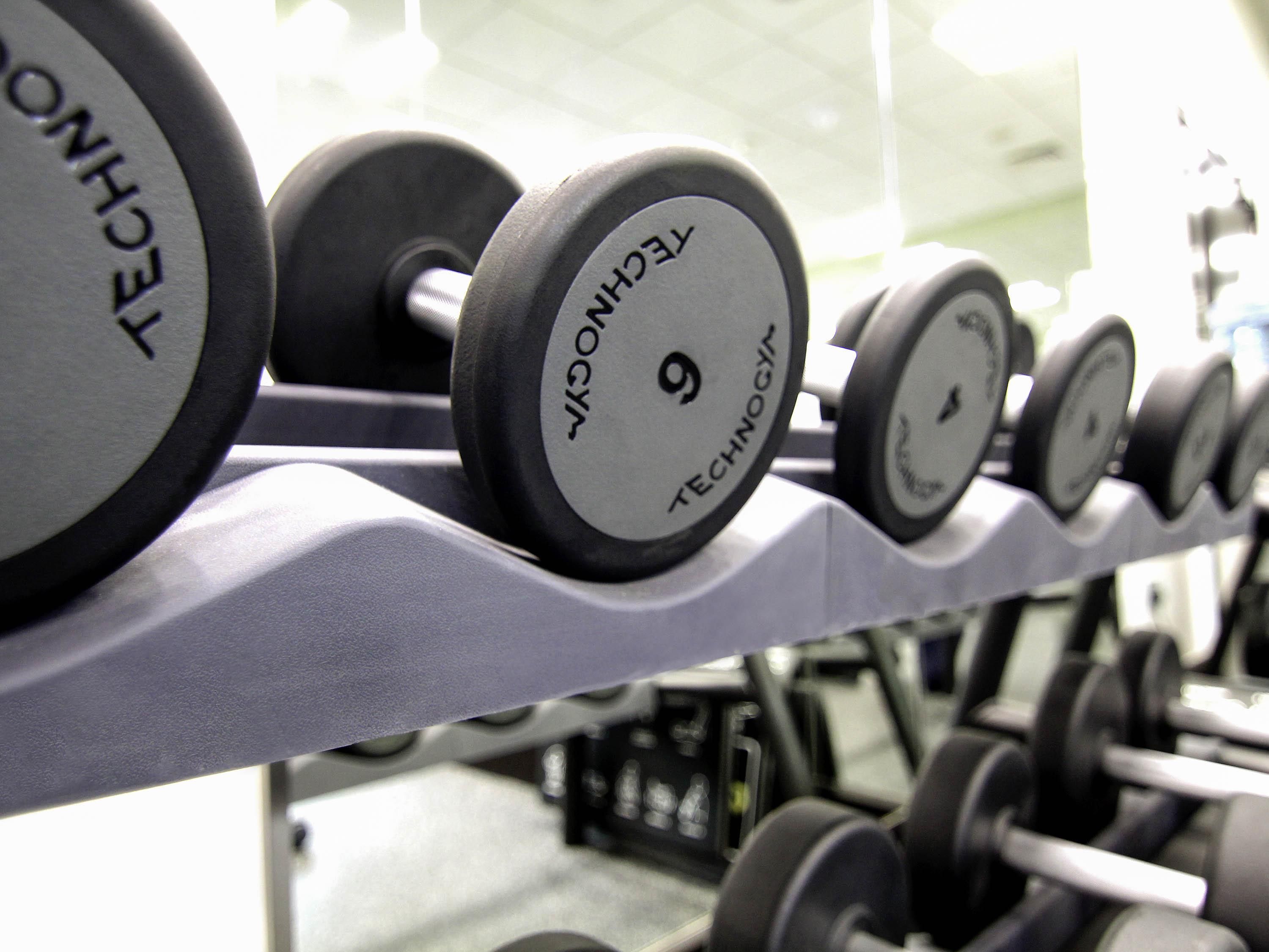 A row of dumbbells with visible weight markings and brand names.