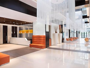 A modern lobby with a reception desk, seating area, and hanging decor. - ibis One Central Hotel (Dubai)