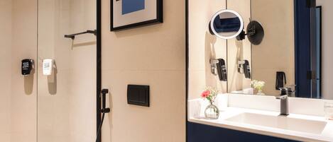 A modern bathroom with a large mirror, a sink, and a shower area.