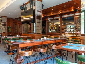 A restaurant with a long communal table, individual booths, and a bar area.