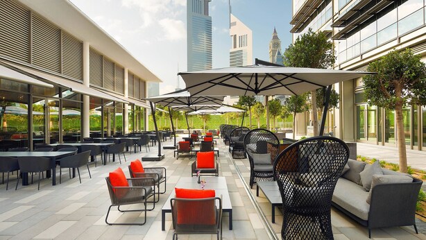 An outdoor patio with tables and chairs, a sofa, and umbrellas.