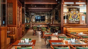 A traditional pub interior with wooden furniture, a long counter, and a coat of arms on the wall.