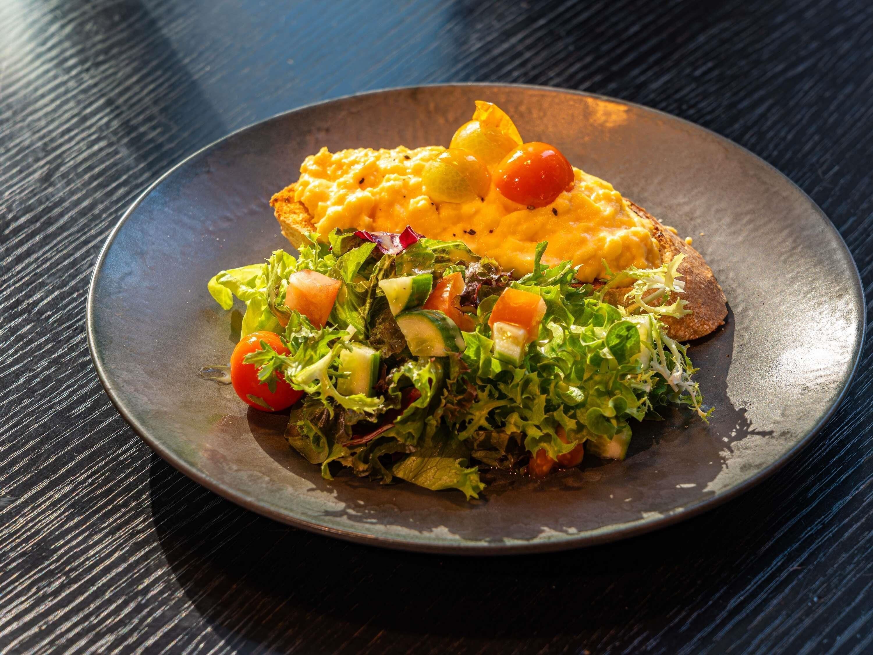 Un plato con huevos revueltos, tostadas y una ensalada.
