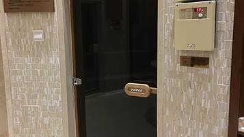 A hotel room entrance with a glass door, a Harvia sauna control panel, and a Harvia logo on the door.