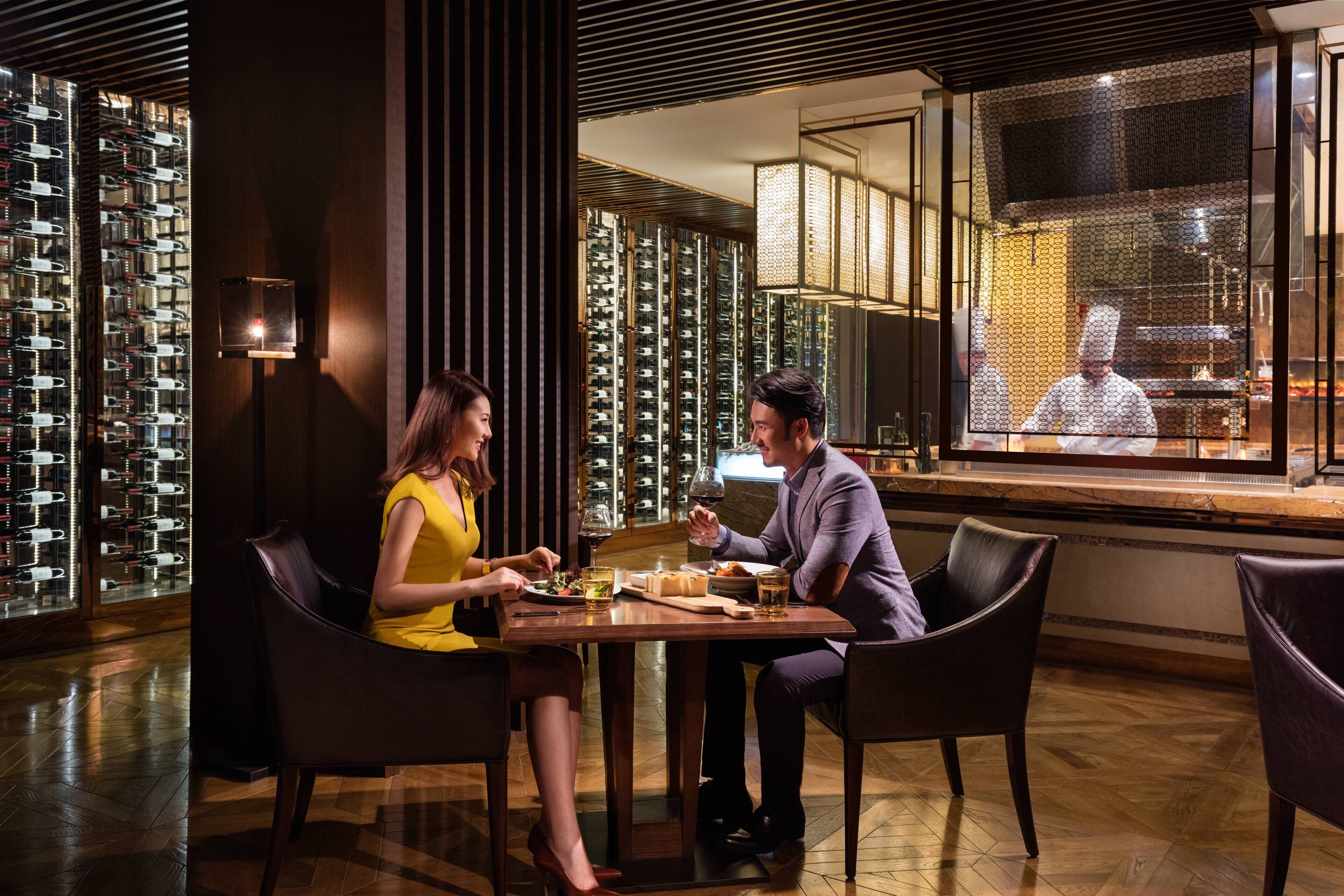Una pareja cenando en una mesa con vistas a un chef en el fondo.