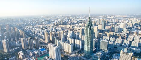 A high-rise building with a unique architectural design, surrounded by a dense urban environment with numerous other high-rise buildings.