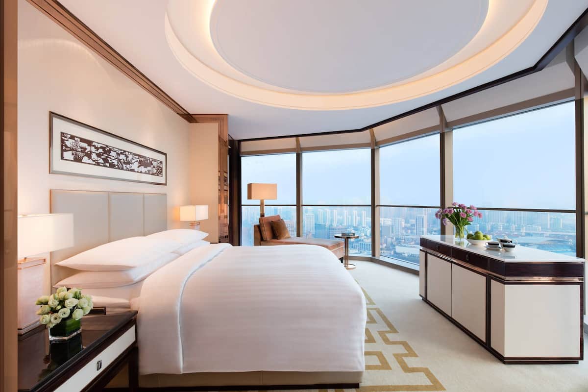 Ein Hotelzimmer mit einem großen Bett, einem Schreibtisch, einem Stuhl und Blick auf die Stadt.