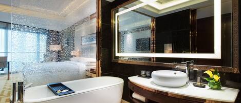 Un baño moderno con una bañera independiente, un espejo grande y un tocador con lavamanos.