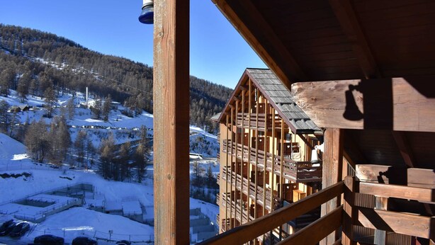Eine Holzhütte mit Blick auf eine verschneite Berglandschaft.