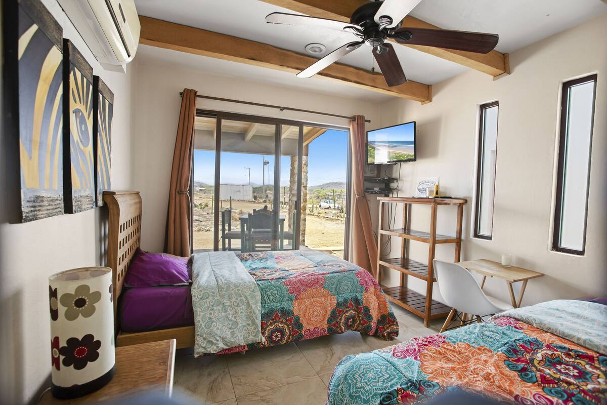 A bedroom with two beds, a desk, a chair, and a ceiling fan.
