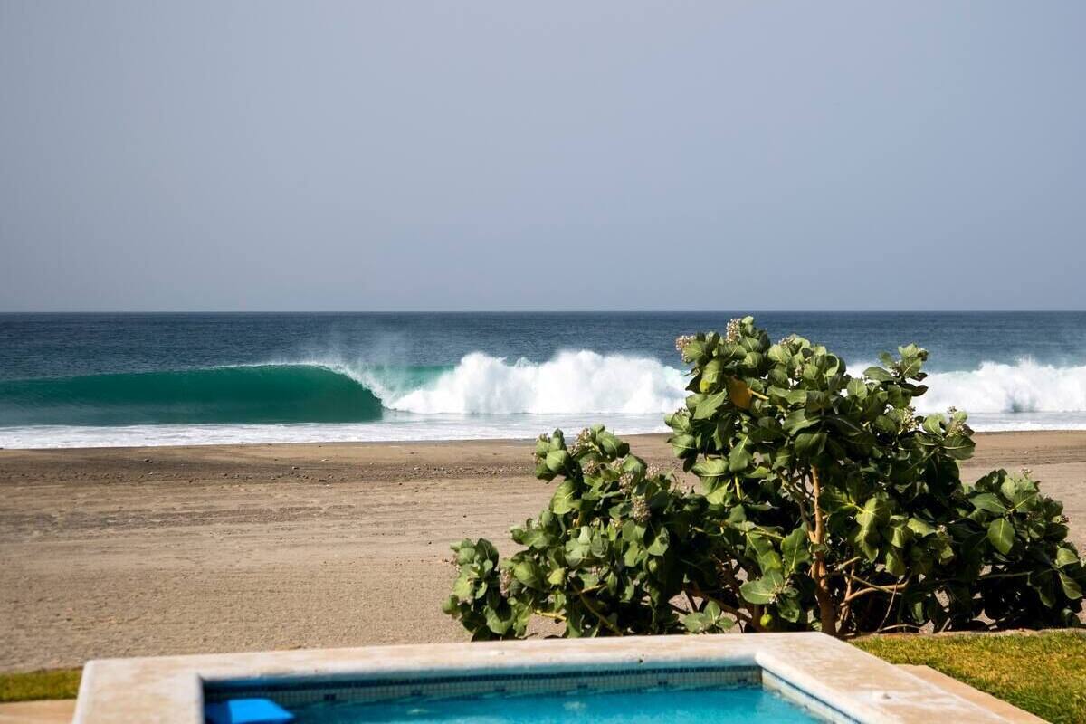 A pool with a view of the ocean and beach.