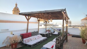 A rooftop terrace with a wooden pergola, lounge chairs, and a small table. - Cádiz INN Hostel (Cádiz)