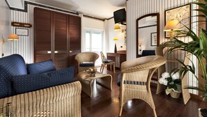 A room with a sofa, wicker chairs, a desk, and a mirror. - Hotel Atilius (Riccione)