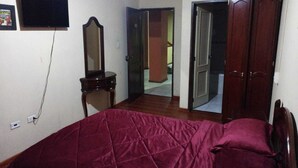 A bedroom with a bed, a dresser, a mirror, and a door leading to another room. - Hotel 4 Ríos (Cuenca)