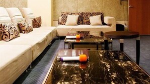 Quarto de hotel moderno com sofá, mesa de centro e porta de madeira.