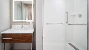A modern bathroom with a white vanity, a mirror, and a glass-enclosed shower.