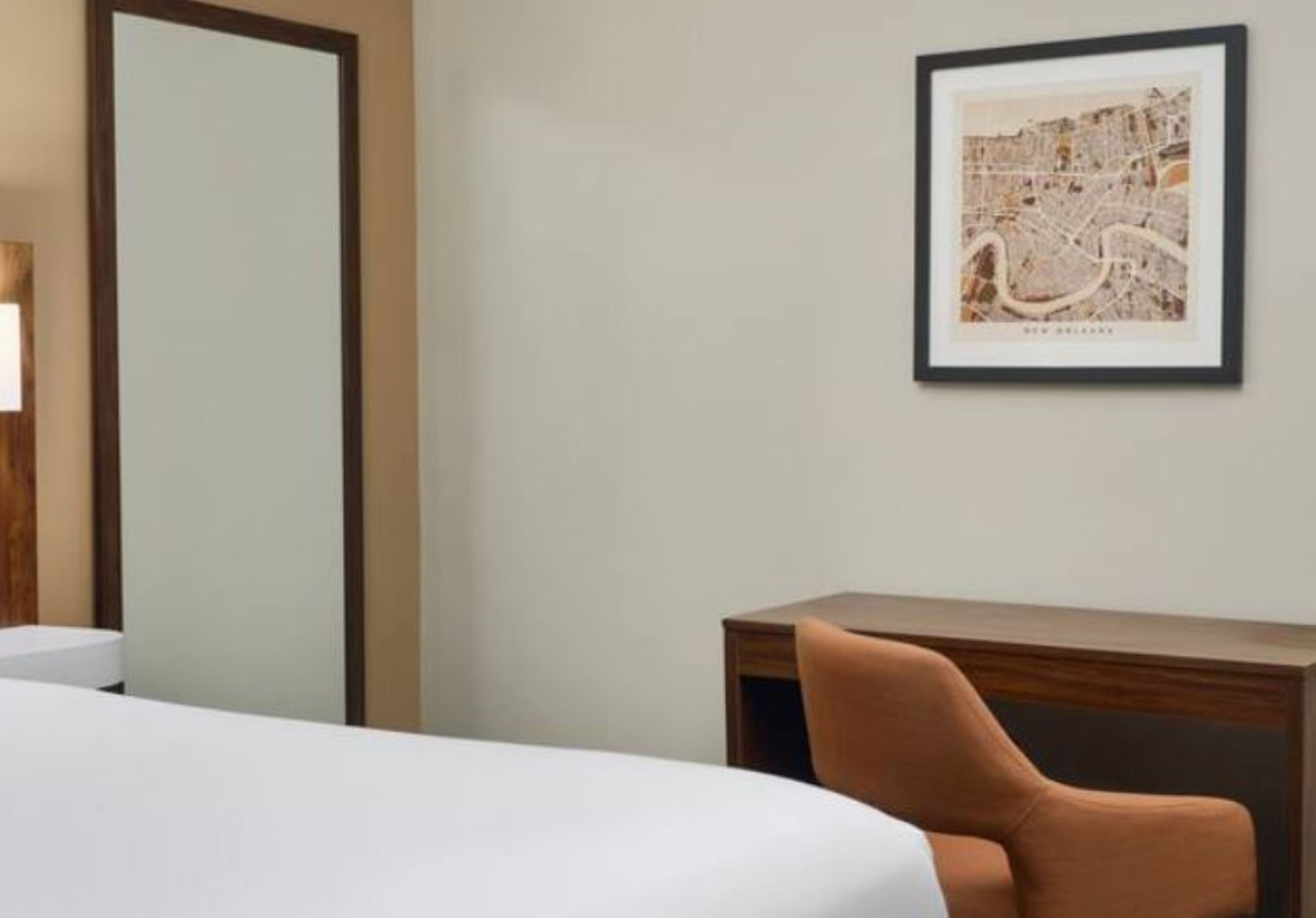 Una habitación de hotel con una cama, un escritorio y un mapa enmarcado en la pared.