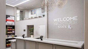 Una zona de recepción con un cartel que dice "Welcome to the Creole State", un mostrador con un teléfono y un cartel de "Treats" al fondo.