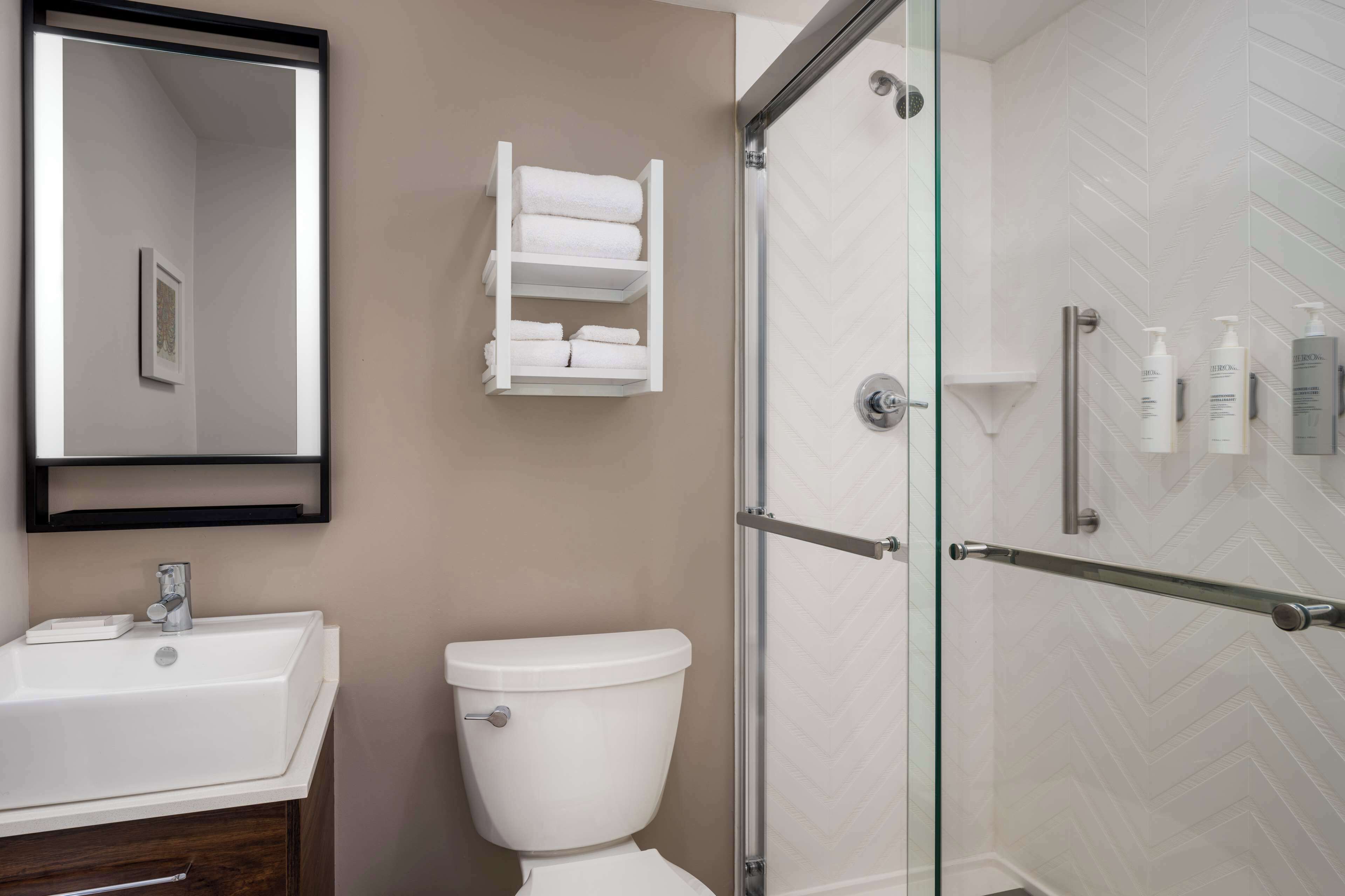 A modern bathroom with a white sink, toilet, and glass shower enclosure.