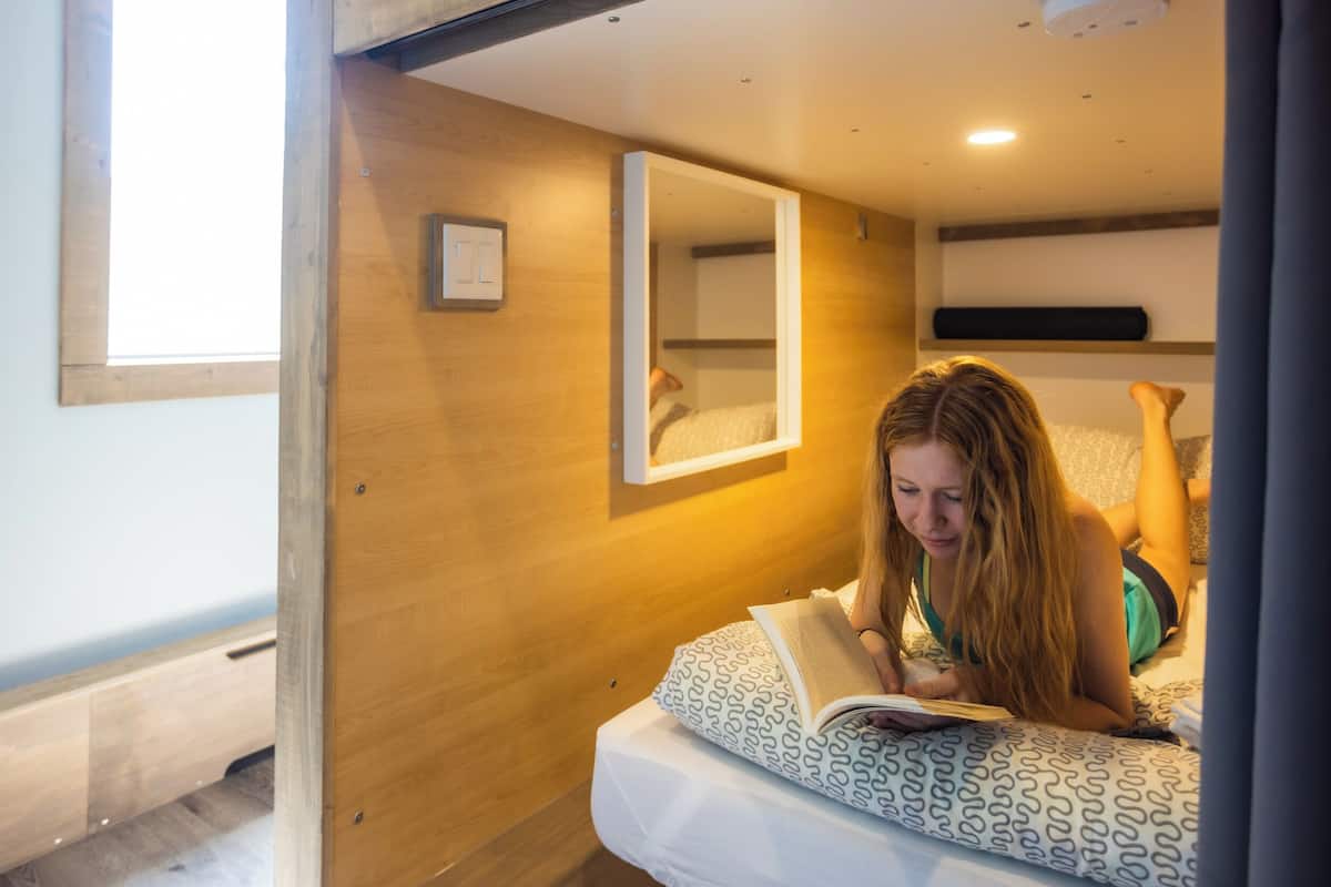 Una habitación con una cama, un espejo y una ventana.