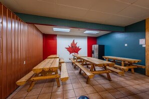 A dining area with wooden picnic tables and a red maple leaf decoration on the wall.