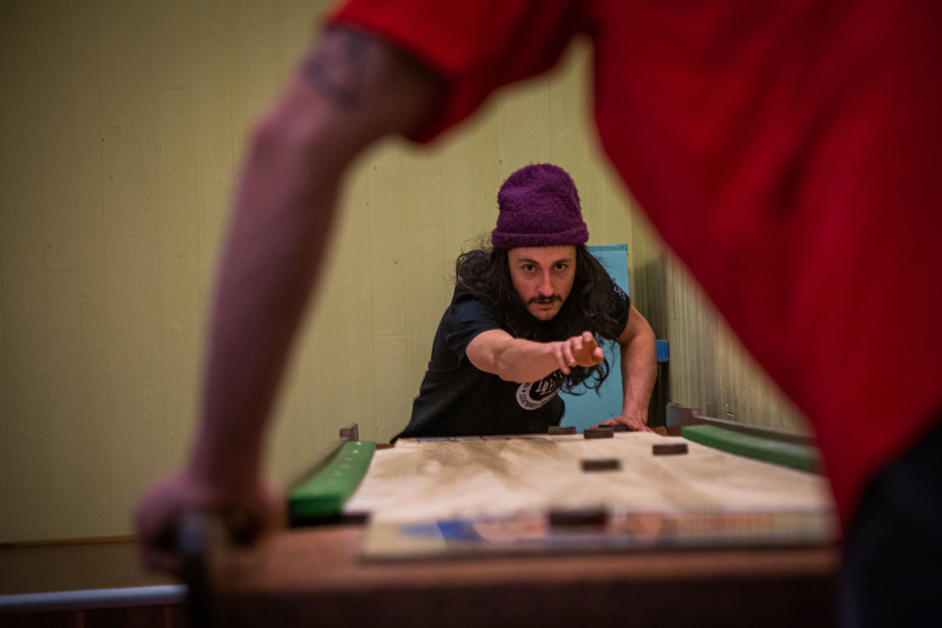 Una persona jugando a un juego en una mesa con superficie de fieltro verde y piezas negras.