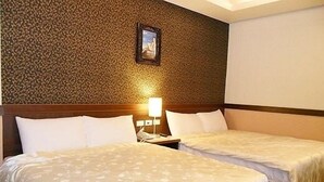 Habitación de hotel con dos camas, cabecero de madera, pared con diseño y un cuadro enmarcado sobre las camas.