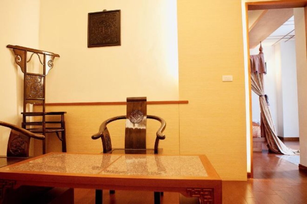 A dining area with a wooden table and chairs, a decorative metal railing, and a framed picture on the wall.