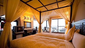 A double bed with a canopy, a desk with a computer, and a window with a view of the city. - Chun Jing Hillview Villa (Ren'ai)