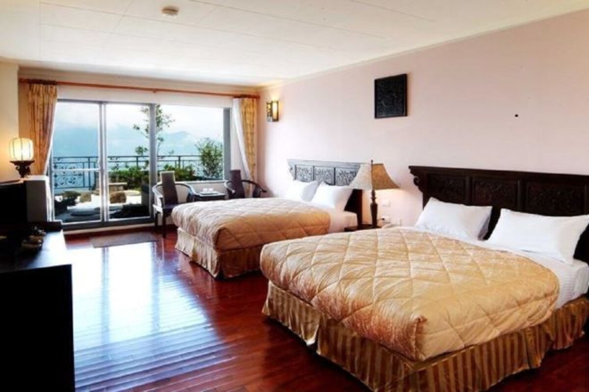 Ein Hotelzimmer mit zwei Betten, einem Fernseher, einem Balkon mit Blick und einem Schreibtisch.