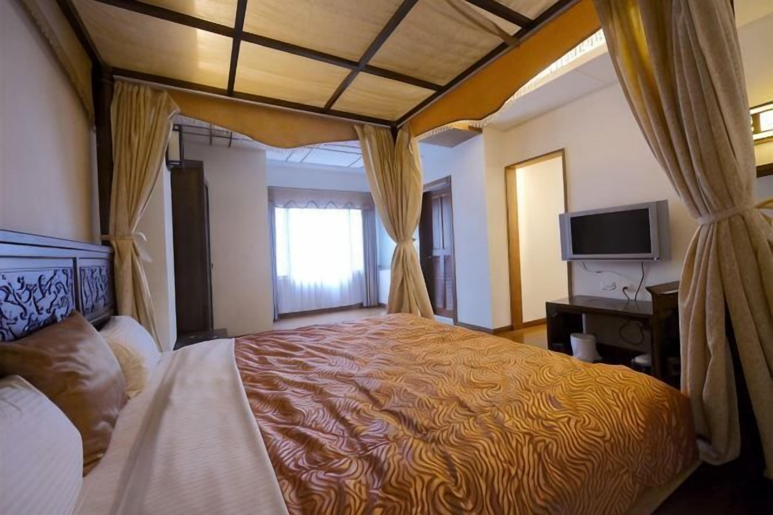 Une chambre d’hôtel avec un grand lit, une télévision et des rideaux.