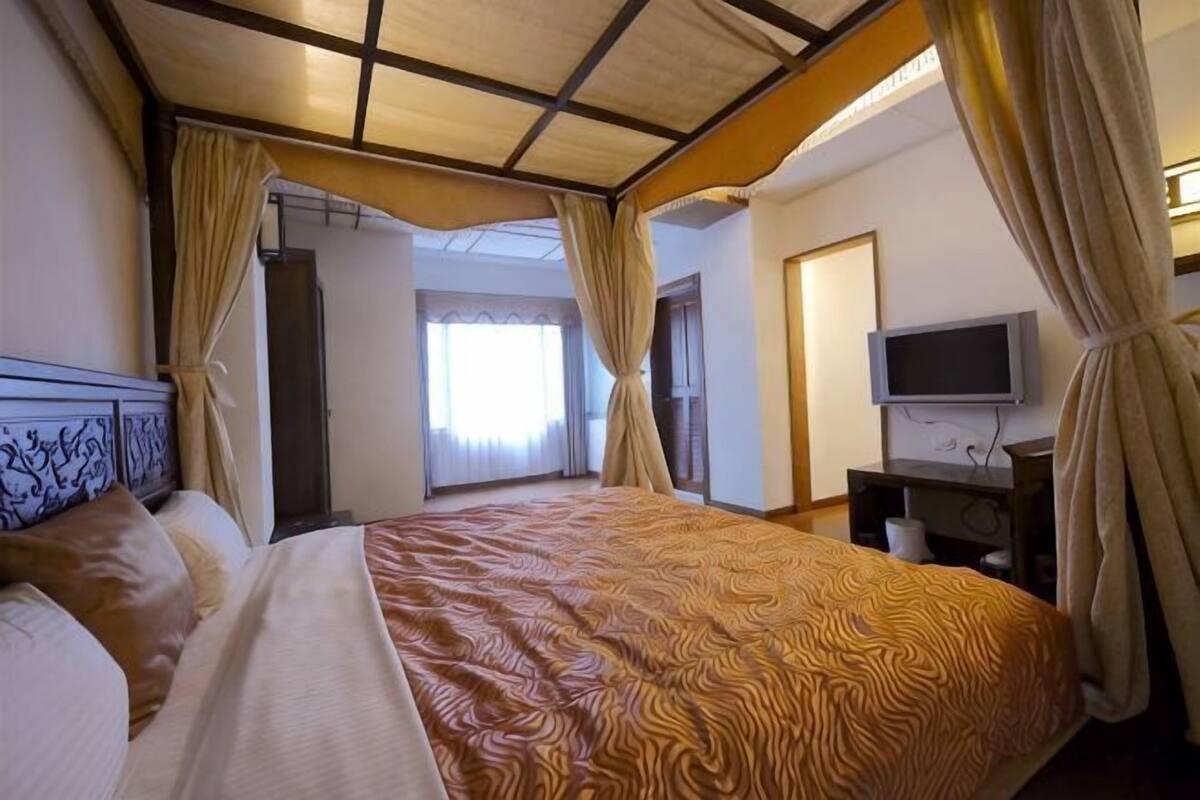 Una habitación de hotel con una cama grande, televisión y cortinas.