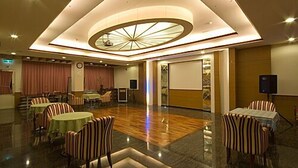 A spacious hotel lobby with a central circular ceiling design, multiple seating areas, and a stage for presentations. - Chun Jing Hillview Villa (Ren'ai)