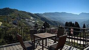 A balcony with a table and chairs overlooking a mountainous landscape. - Chun Jing Hillview Villa (Ren'ai)