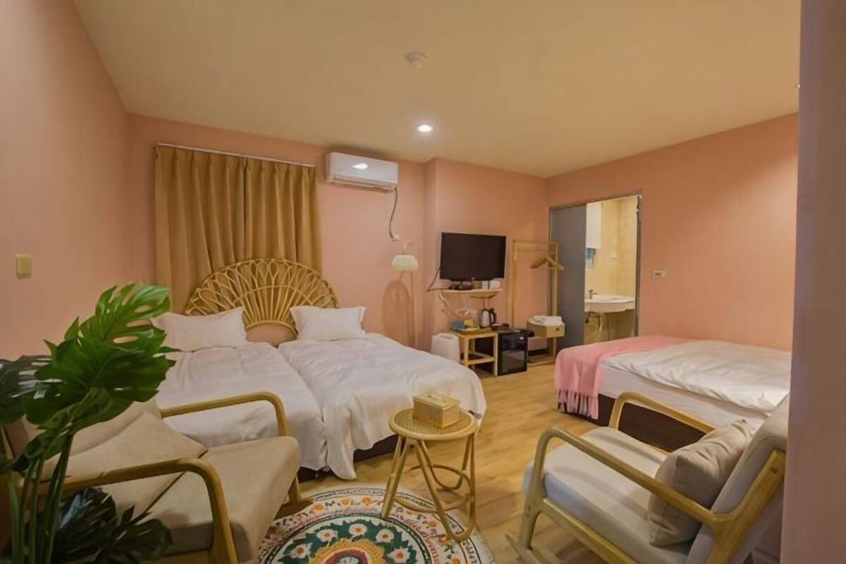 A hotel room with two beds, a small table, a chair, a TV, and a mirror.