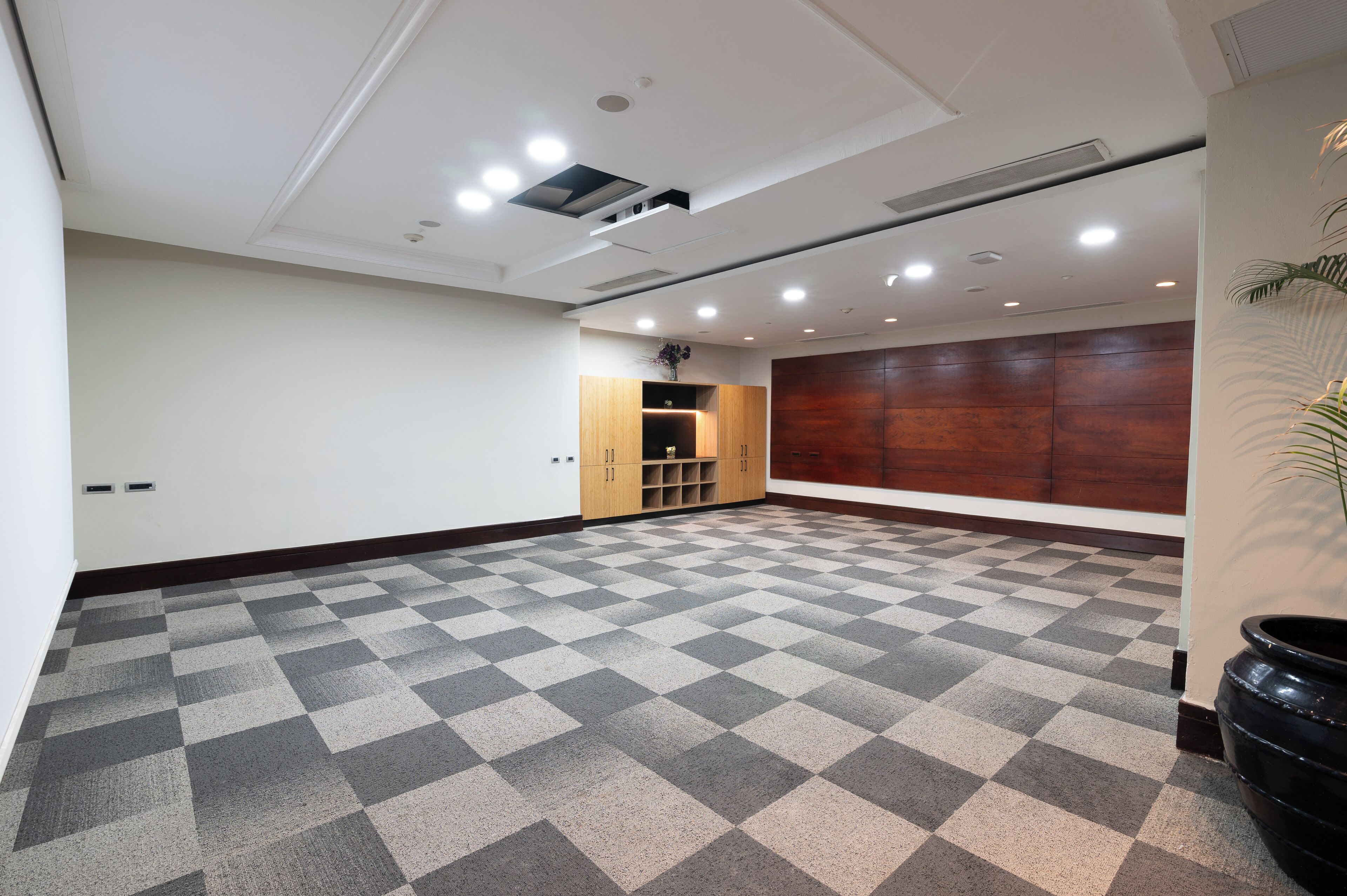 A spacious room with a checkered floor, wooden cabinets, and a large wooden panel wall.