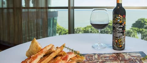 Una mesa con una tabla de embutidos, una botella de vino y una copa de vino.