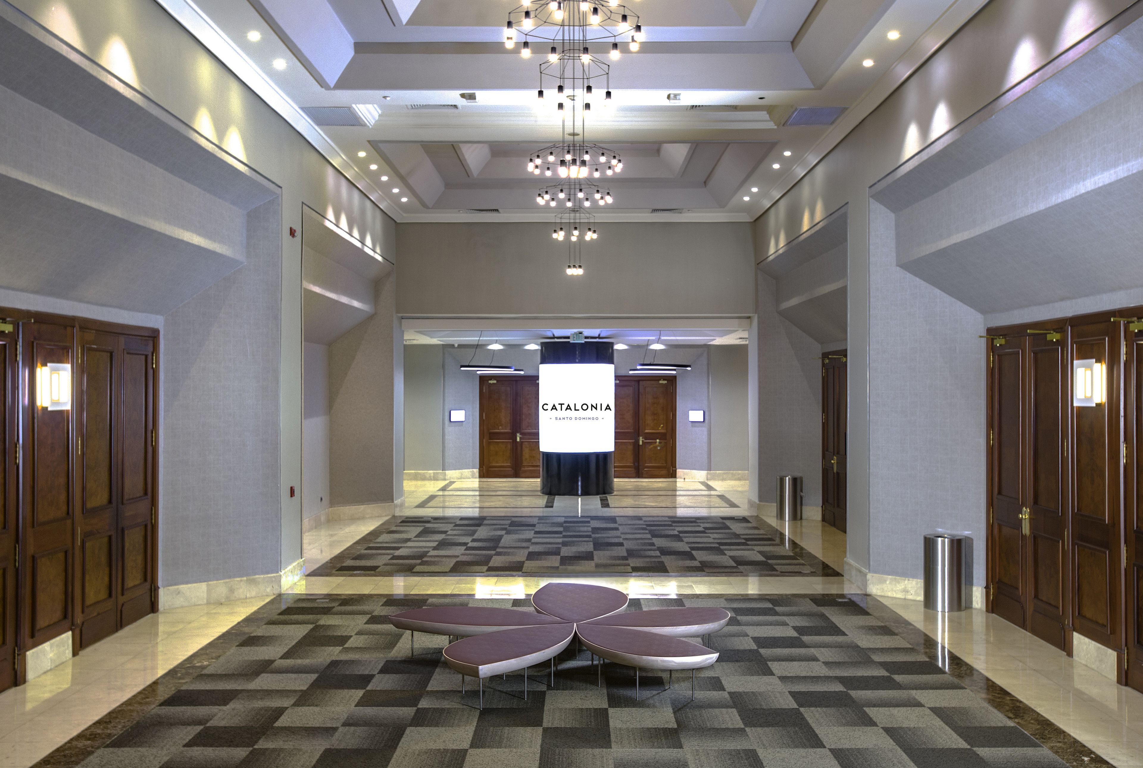A hotel lobby with a checkered floor, a central seating area, and a chandelier.