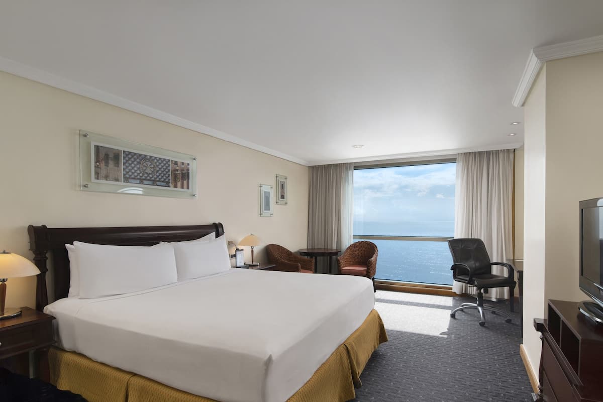 Une chambre d’hôtel avec un grand lit, une télévision, un bureau et une vue sur l’océan.