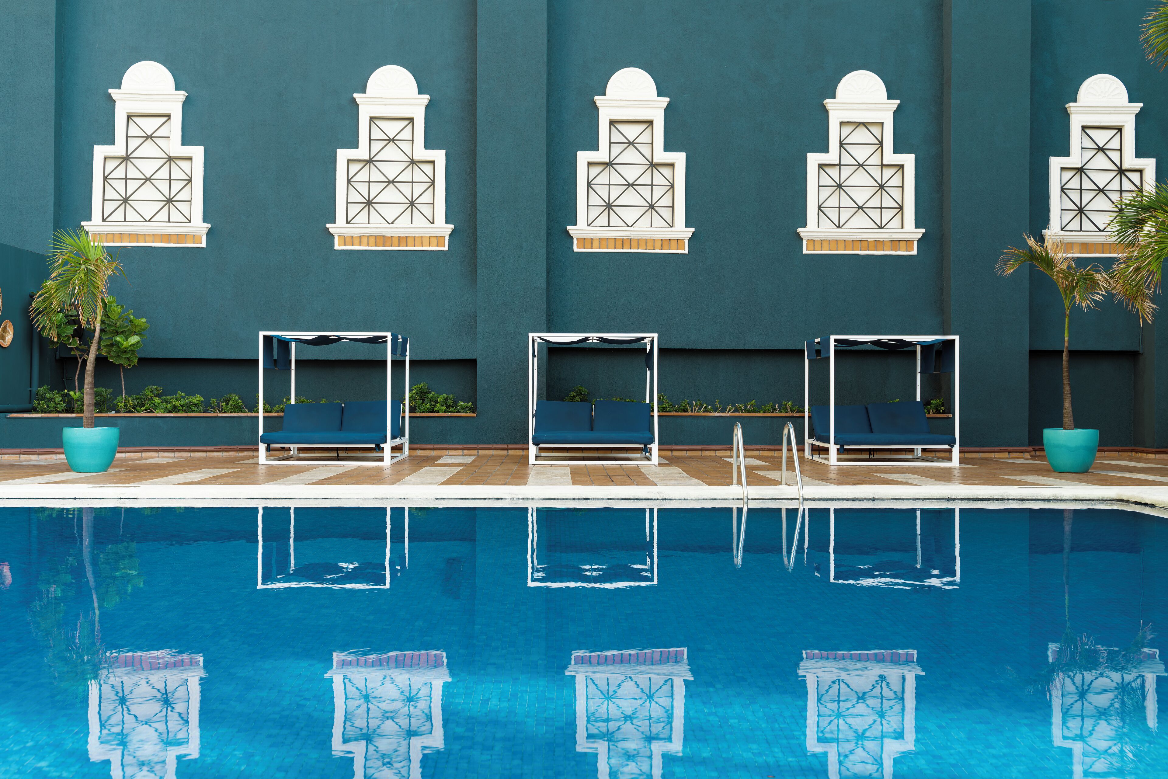 Ein Poolbereich mit blauen Liegestühlen und dem Spiegelbild des Pool-Designs im Wasser.